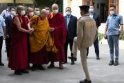 Сотрудник службы безопасности приветствует Его Святейшество Далай-ламу, который идет из своей резиденции в главный тибетский храм, чтобы даровать ежегодные учения по случаю Дня рождения, пробуждения и ухода в махапаринирвану Будды Шакьямуни. Дхарамсала, штат Химачал-Прадеш, Индия. 4 июня 2023 г. Фото: Тензин Чойджор (офис ЕСДЛ).
