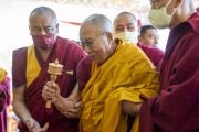 Покидая сцену по завершении учений на стадионе «Палджор», Его Святейшество Далай-лама благословляет молитвенный барабан. Гангток, штат Сикким, Индия. 12 декабря 2023 г. Фото: Тензин Чойджор (офис ЕСДЛ).