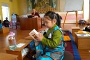 Юная участница ретрита читает детский молитвенный сборник, специально напечатанный для детей. Фото: Тензин Рабьянг, Тибетский дом (Дели)