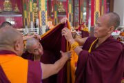 Участникам церемонии дарования обетов полностью посвященных монахов, проводимой Его Святейшеством Далай-ламой на площадке для философских диспутов монастыря Дрепунг Гоманг, помогают надеть освященные монашеские одеяния. Мундгод, штат Карнатака, Индия. 25 декабря 2025 г. Фото: Тензин Чойджор